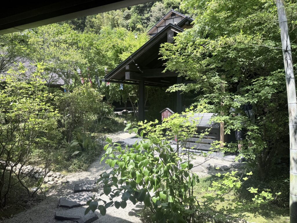 箱根湯寮のテラス席から望む、深い緑に囲まれた静かな日本庭園。自然光が最適化された、リラックス専用の外部インターフェース。